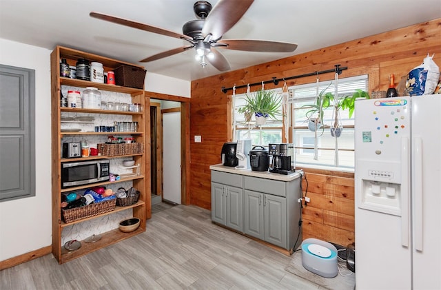 3020 62nd St, Des Moines, IA 50322 - kitchen with white refrigerator with ice dispenser, stainless steel microwave, gray cabinetry, open shelves, and wood walls