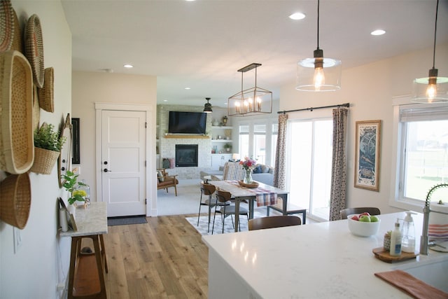 3338 9th Ave SW, Altoona, IA 50009 - kitchen with a large fireplace, light wood-style flooring, hanging light fixtures, recessed lighting, and a sink