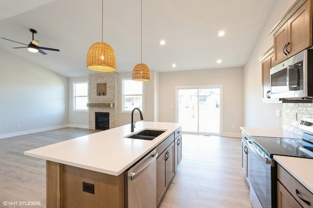 3412 5th Ave SE, Altoona, IA 50009 - kitchen featuring stainless steel appliances, a sink, light wood finished floors, a stone fireplace, and recessed lighting