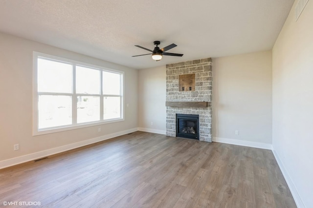 3418 5th Ave SE, Altoona, IA 50009 - unfurnished living room featuring ceiling fan, wood finished floors, a stone fireplace, and baseboards