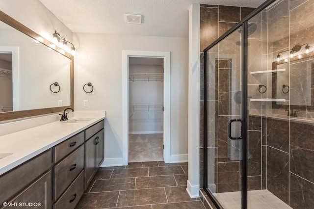 3418 5th Ave SE, Altoona, IA 50009 - bathroom featuring double vanity, a spacious closet, a stall shower, a textured ceiling, and baseboards