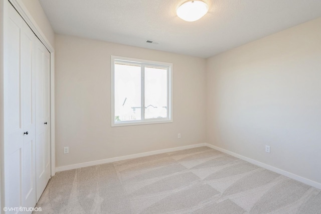 3418 5th Ave SE, Altoona, IA 50009 - unfurnished bedroom with light colored carpet, a closet, baseboards, and a textured ceiling