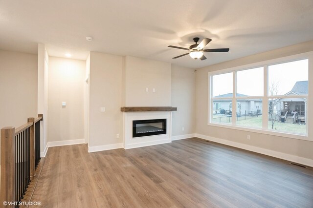 3424 5th Ave SE, Altoona, IA 50009 - unfurnished living room with a glass covered fireplace, wood finished floors, ceiling fan, and baseboards