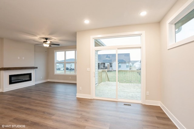 3424 5th Ave SE, Altoona, IA 50009 - unfurnished living room featuring a glass covered fireplace, dark wood-type flooring, ceiling fan, baseboards, and recessed lighting