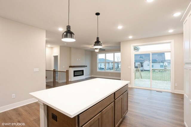 3424 5th Ave SE, Altoona, IA 50009 - kitchen with wood finished floors, a ceiling fan, a glass covered fireplace, light countertops, and decorative light fixtures