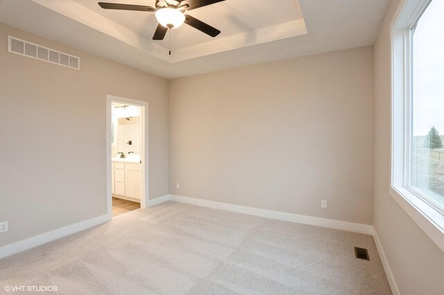 3424 5th Ave SE, Altoona, IA 50009 - spare room with light carpet, a tray ceiling, a ceiling fan, and baseboards