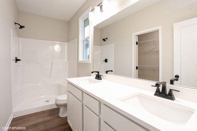 3424 5th Ave SE, Altoona, IA 50009 - bathroom featuring a shower, toilet, wood finished floors, and double vanity