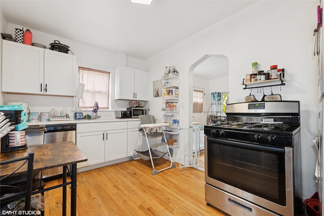 5713 Clark Blvd, Des Moines, IA 50311 - kitchen with stainless steel appliances, arched walkways, white cabinets, and light wood-style flooring