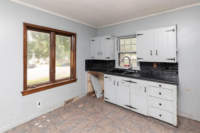 2721 Cornell St, Des Moines, IA 50313 - kitchen with a sink, dark countertops, ornamental molding, tasteful backsplash, and white cabinetry
