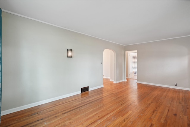105 N Park Lane Dr, Knoxville, IA 50138 - empty room featuring arched walkways, crown molding, baseboards, and light wood-style floors