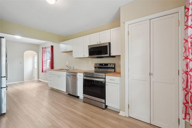 105 N Park Lane Dr, Knoxville, IA 50138 - kitchen featuring stainless steel appliances, arched walkways, white cabinets, and light wood finished floors