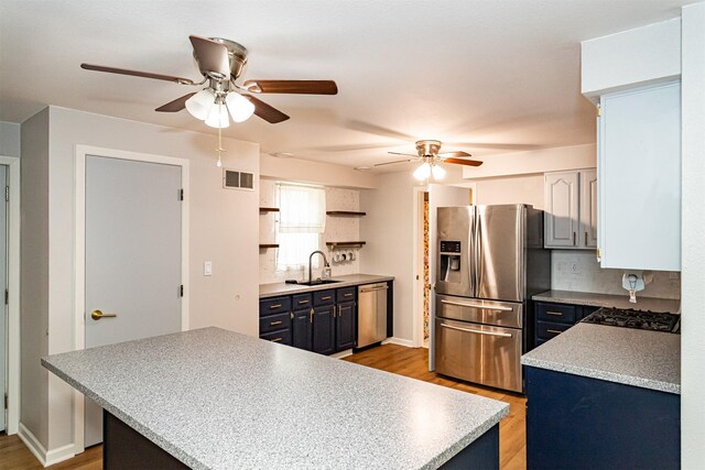 1717 Linn St, Boone, IA 50036 - kitchen with stainless steel appliances, a ceiling fan, decorative backsplash, light wood finished floors, and a sink