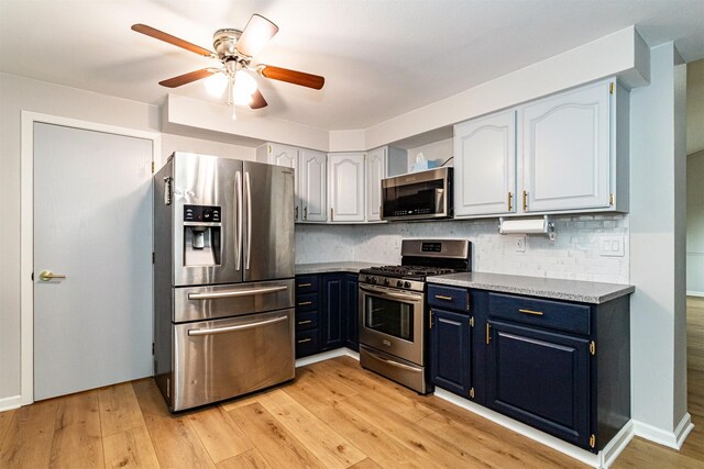 1717 Linn St, Boone, IA 50036 - kitchen with appliances with stainless steel finishes, blue cabinets, tasteful backsplash, ceiling fan, and light wood finished floors