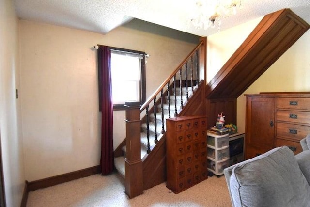 231 S 1st St, Ogden, IA 50212 - staircase with a chandelier, carpet, a textured ceiling, and baseboards