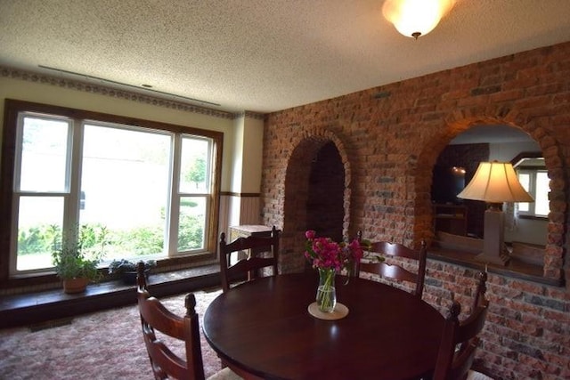 231 S 1st St, Ogden, IA 50212 - dining area with a textured ceiling, arched walkways, and brick wall