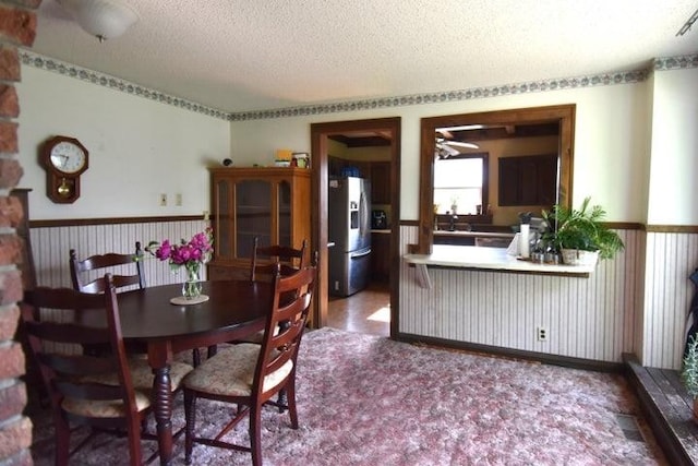 231 S 1st St, Ogden, IA 50212 - dining space featuring a textured ceiling, a wainscoted wall, and ceiling fan
