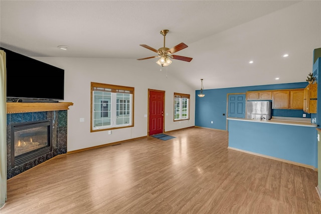 810 NE 5th St, Ankeny, IA 50021 - unfurnished living room featuring lofted ceiling, ceiling fan, light wood-type flooring, a tiled fireplace, and baseboards