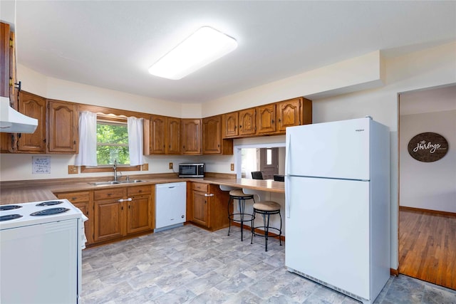 403 S Elm St, Lamoni, IA 50140 - kitchen featuring white appliances, a sink, brown cabinetry, range hood, and stone finish flooring