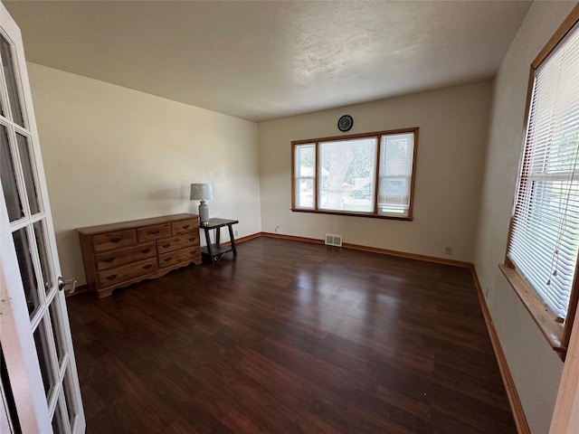 702 N 2nd Ave, Winterset, IA 50273 - spare room featuring dark wood-style flooring, plenty of natural light, and baseboards
