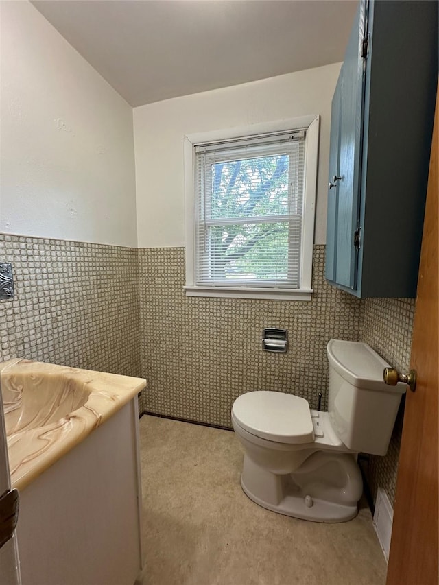 702 N 2nd Ave, Winterset, IA 50273 - half bathroom with toilet, tile walls, vanity, and a wainscoted wall