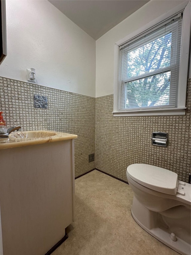 702 N 2nd Ave, Winterset, IA 50273 - half bathroom featuring toilet, vanity, a wainscoted wall, and tile walls