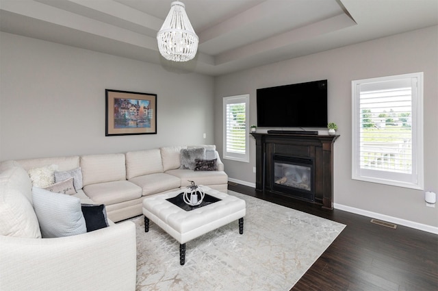 1245 Blue Bonnet Dr, Carlisle, IA 50047 - living area with a chandelier, baseboards, a tray ceiling, dark wood-type flooring, and a glass covered fireplace