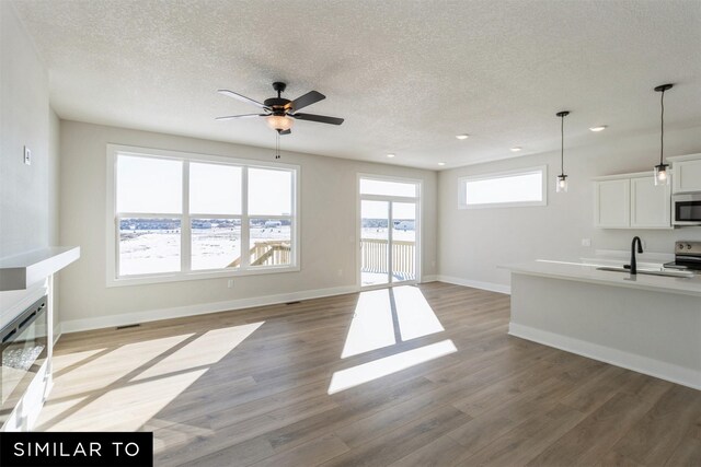 4208 NE 5th St, Ankeny, IA 50021 - unfurnished living room featuring a ceiling fan, a sink, light wood-type flooring, a textured ceiling, and recessed lighting