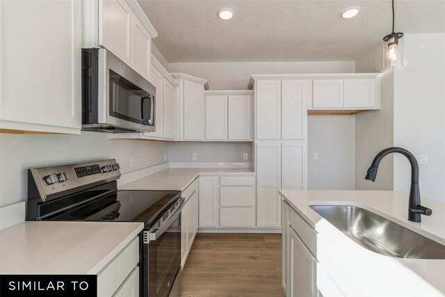 4208 NE 5th St, Ankeny, IA 50021 - kitchen with stainless steel appliances, a sink, white cabinetry, light wood-style flooring, and decorative light fixtures