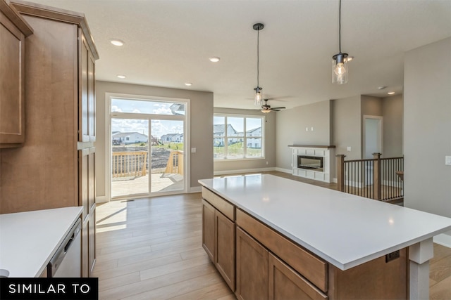 4212 NE 5th St, Ankeny, IA 50021 - kitchen featuring ceiling fan, a glass covered fireplace, light wood-type flooring, light countertops, and a kitchen island