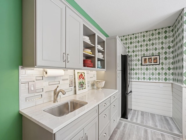 15075 Sheridan Ave, Clive, IA 50325 - kitchen featuring wallpapered walls, a sink, freestanding refrigerator, open shelves, and light stone countertops