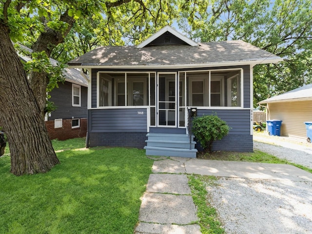 3018 Woodland Ave, Des Moines, IA 50312 - bungalow featuring a sunroom, a shingled roof, a front lawn, and entry steps