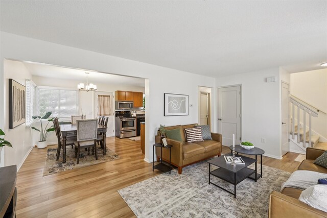 2501 SE 18th Ct, Des Moines, IA 50320 - living area with a chandelier, stairs, light wood-style floors, and baseboards
