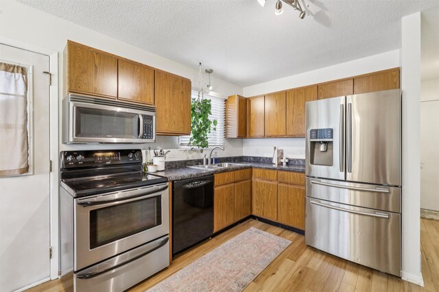 2501 SE 18th Ct, Des Moines, IA 50320 - kitchen featuring appliances with stainless steel finishes, a sink, dark countertops, brown cabinets, and light wood finished floors