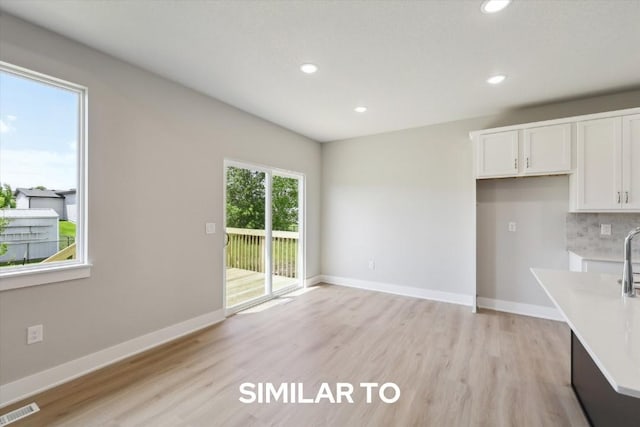 214 Cedar Dr, Gilbert, IA 50105 - kitchen with white cabinets, recessed lighting, light wood-style floors, light countertops, and baseboards