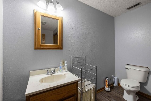 1863 Glenwood Cir, Des Moines, IA 50320 - bathroom featuring toilet, vanity, wood finished floors, a textured ceiling, and baseboards