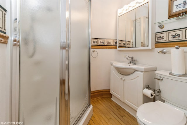 1723 6th St, Perry, IA 50220 - full bathroom featuring a shower stall, vanity, toilet, wood finished floors, and baseboards