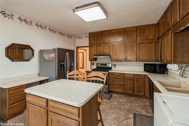 1723 6th St, Perry, IA 50220 - kitchen with black appliances, washer / dryer, a sink, under cabinet range hood, and tasteful backsplash