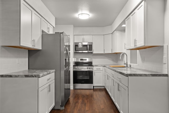 817 Roberts Ter, Marshalltown, IA 50158 - kitchen with appliances with stainless steel finishes, a sink, tasteful backsplash, white cabinetry, and dark wood-type flooring