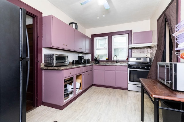3417 6th Ave, Des Moines, IA 50313 - kitchen featuring stainless steel range with gas cooktop, freestanding refrigerator, light wood-style flooring, and under cabinet range hood