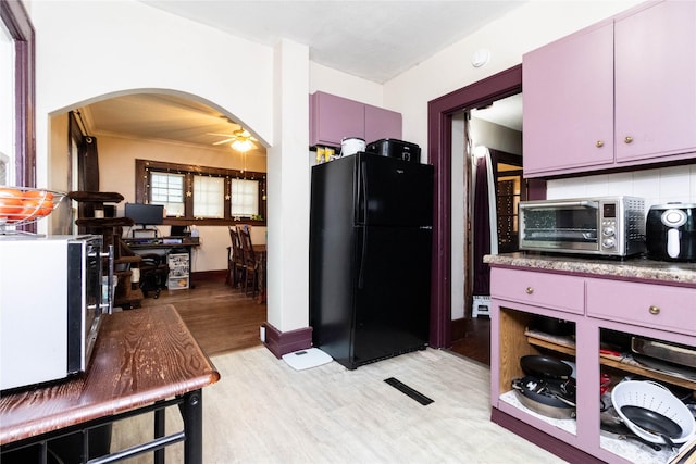 3417 6th Ave, Des Moines, IA 50313 - kitchen featuring freestanding refrigerator, arched walkways, light wood-type flooring, a ceiling fan, and baseboards