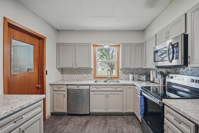 417 NE 2nd St, Panora, IA 50216 - kitchen with appliances with stainless steel finishes, a sink, decorative backsplash, a paneled ceiling, and dark wood-style flooring