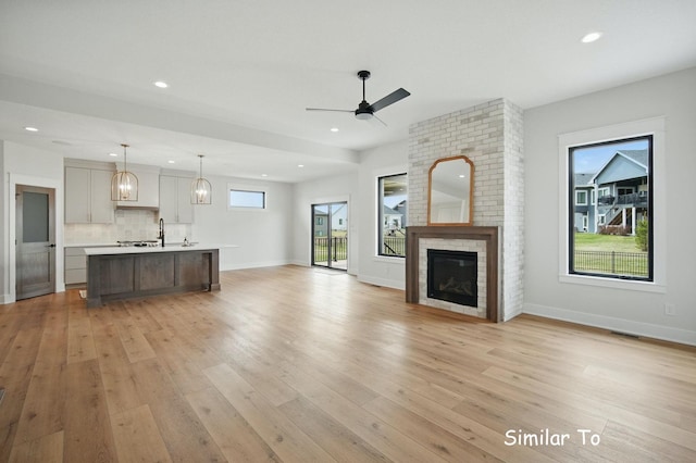 1801 Summit Cir NE, Bondurant, IA 50035 - unfurnished living room with light wood-style flooring, a ceiling fan, plenty of natural light, recessed lighting, and a fireplace