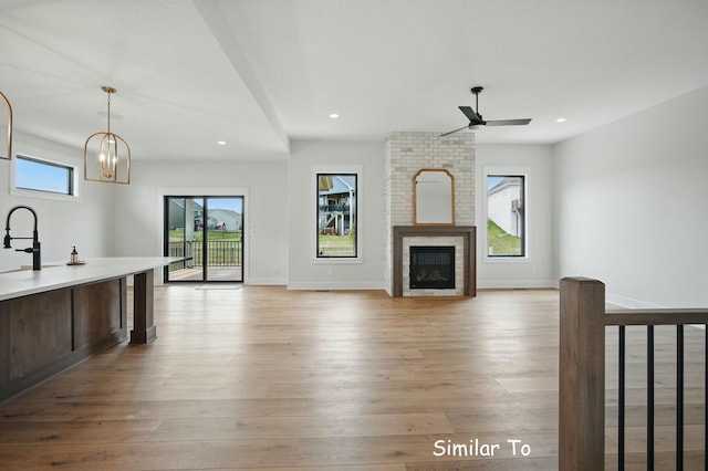 1801 Summit Cir NE, Bondurant, IA 50035 - unfurnished living room featuring light wood finished floors, ceiling fan, recessed lighting, a brick fireplace, and a chandelier