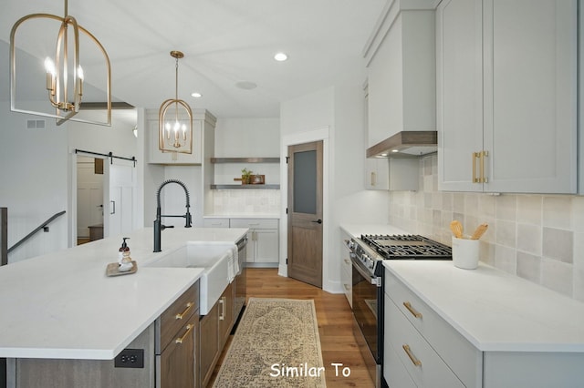 1801 Summit Cir NE, Bondurant, IA 50035 - kitchen with stainless steel range with gas stovetop, a barn door, a sink, light countertops, and decorative backsplash