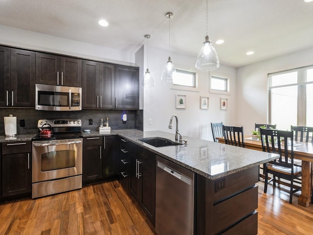 4485 NW 167th St, Clive, IA 50325 - kitchen with appliances with stainless steel finishes, a sink, a peninsula, decorative backsplash, and dark wood-type flooring