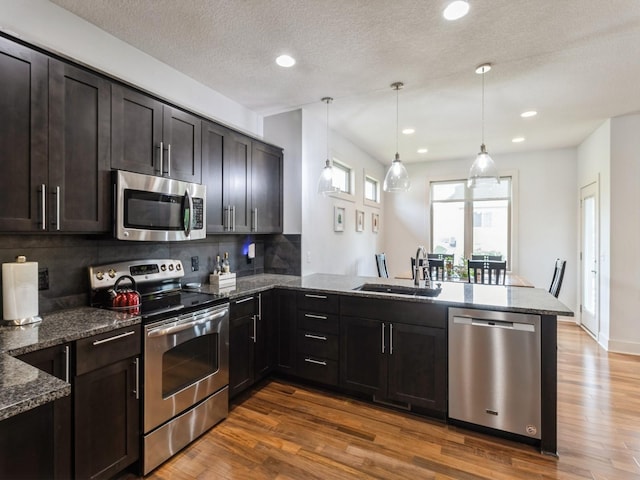 4485 NW 167th St, Clive, IA 50325 - kitchen featuring appliances with stainless steel finishes, a sink, a peninsula, dark stone countertops, and recessed lighting