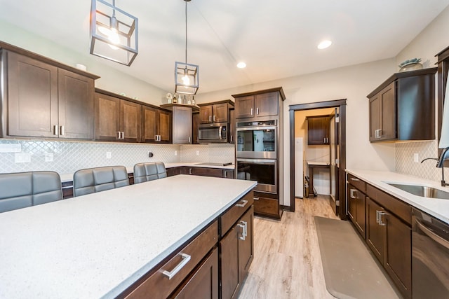 2502 Eagle Ridge Dr, Granger, IA 50109 - kitchen with stainless steel appliances, a sink, light wood-style floors, dark brown cabinets, and decorative backsplash