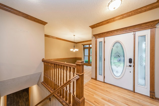 8148 Durham Cir, Johnston, IA 50131 - entryway featuring a chandelier, light wood finished floors, crown molding, and a textured ceiling