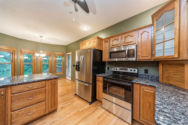 8148 Durham Cir, Johnston, IA 50131 - kitchen with appliances with stainless steel finishes, ceiling fan, light wood-style floors, glass insert cabinets, and dark stone countertops