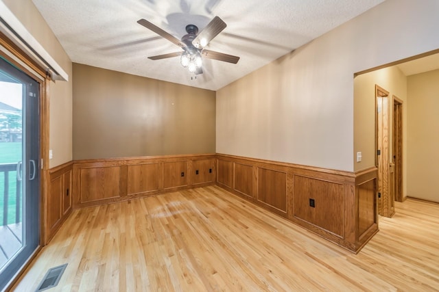 8148 Durham Cir, Johnston, IA 50131 - spare room featuring light wood-style floors, a wainscoted wall, a textured ceiling, and a ceiling fan